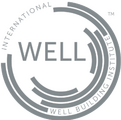 WELL Logo: A minimalist grey logo featuring a circular, segmented ring design with the word "WELL" in a clean sans-serif font in the center; the text "INTERNATIONAL WELL BUILDING INSTITUTE™" follows the curve of the outer ring.