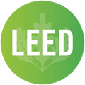 LEED Logo: A green circular logo featuring a light green oak leaf in the center with the word "LEED" in bold, white sans-serif lettering overlaid on top.